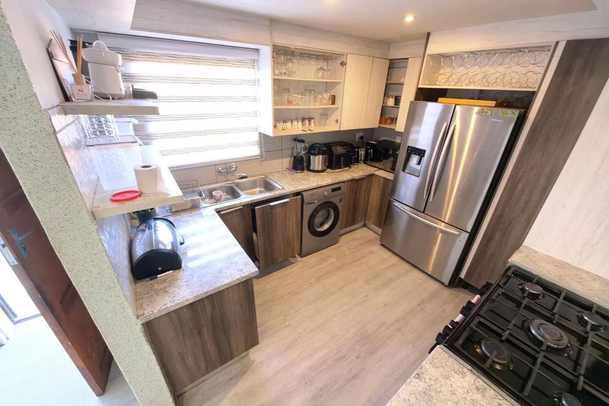 A functional kitchen featuring stone countertops, built-in cabinetry, a gas hob, and integrated laundry facilities, offering a practical and well-organized workspace.