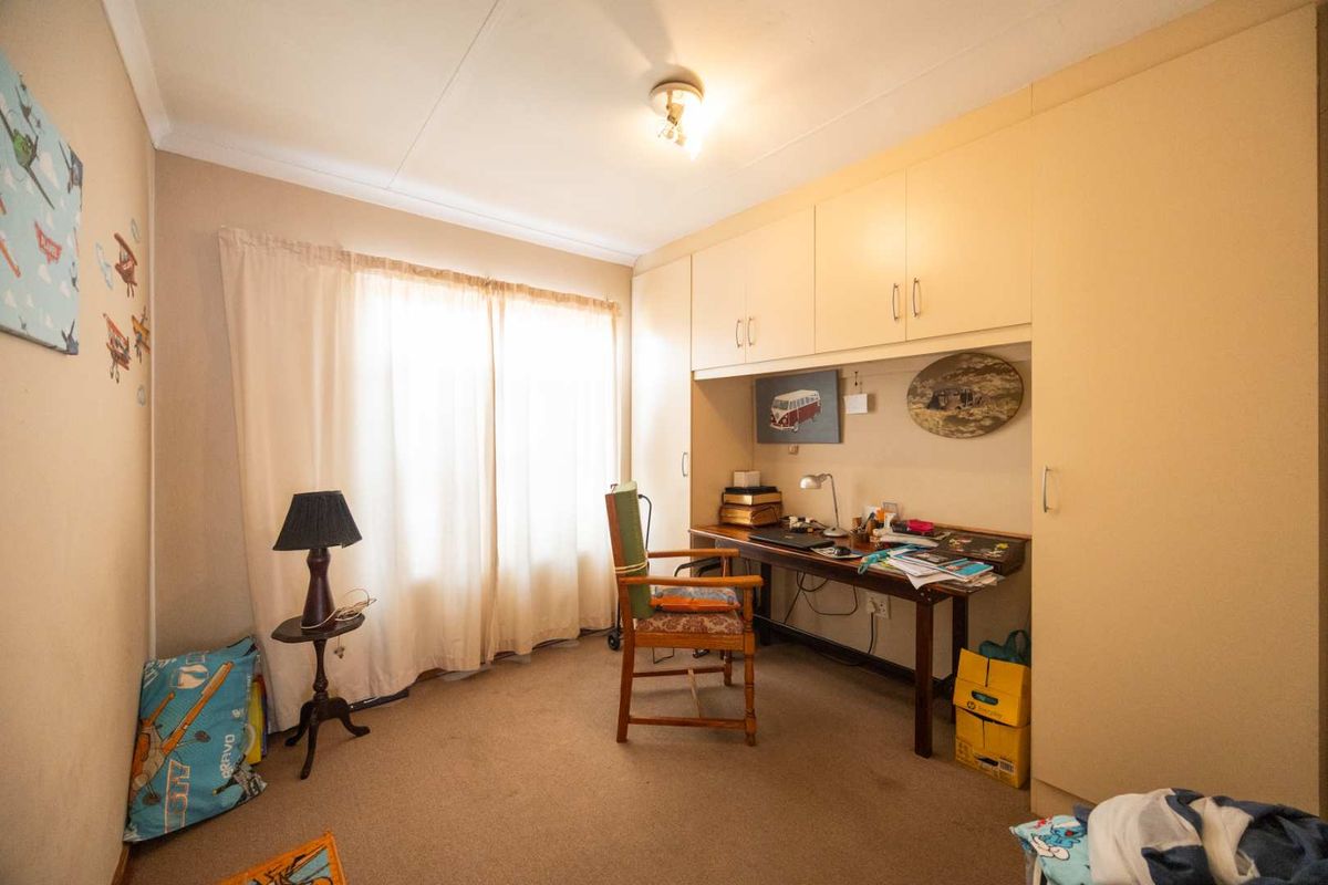 A bedroom featuring built-in cupboards and carpeted flooring, offering a functional space with natural light from the window.