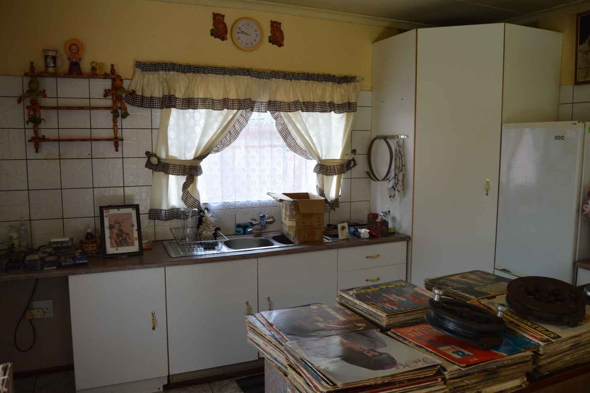 A dated kitchen featuring original cabinetry, a stainless steel sink, and tiled backsplash, offering significant potential for a modern renovation.