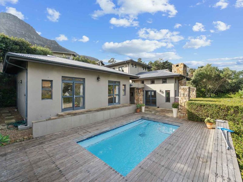 Outdoor pool area featuring timber decking, stone accents, and direct access to the home through multiple sets of french doors.