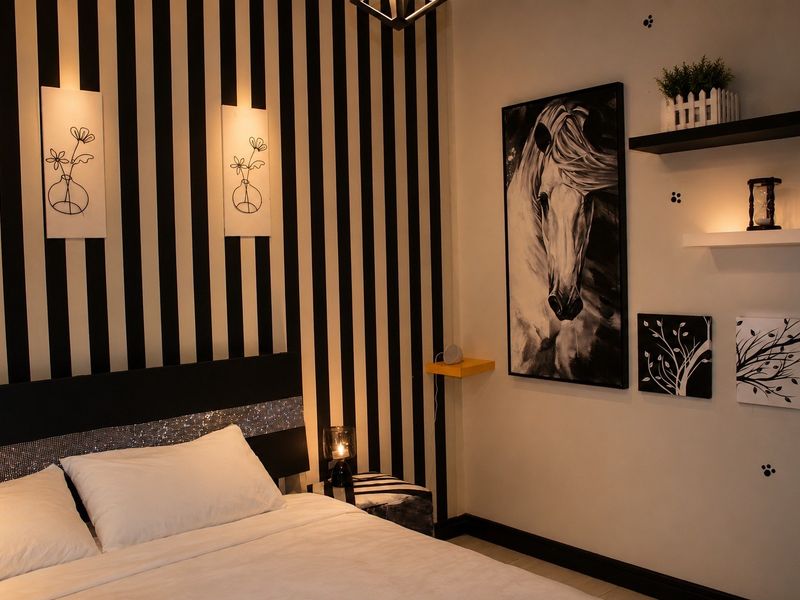 A well-maintained bedroom featuring a striking black and white striped accent wall and built-in wall shelving.