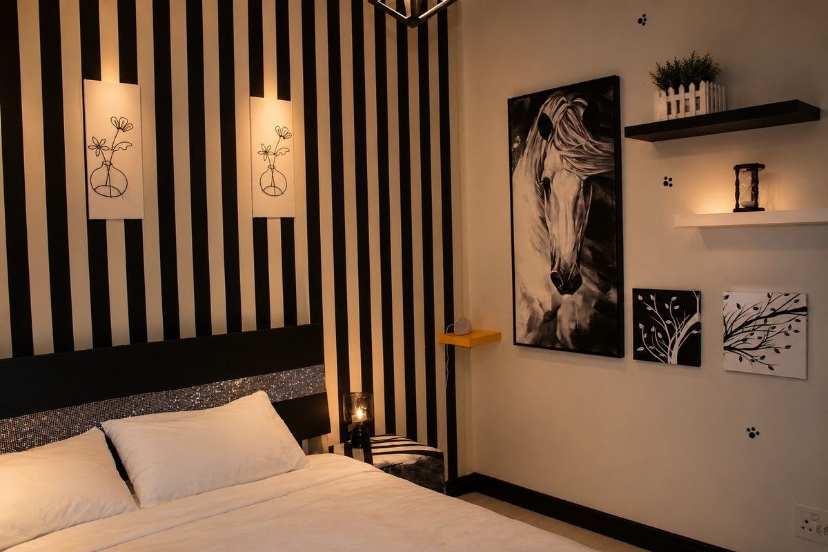 A well-maintained bedroom featuring a striking black and white striped accent wall and built-in wall shelving.
