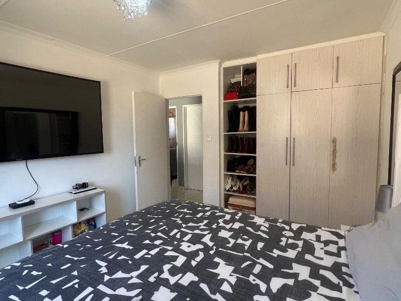 A well-maintained bedroom featuring built-in cupboards with integrated shelving and a modern ceiling light fixture.