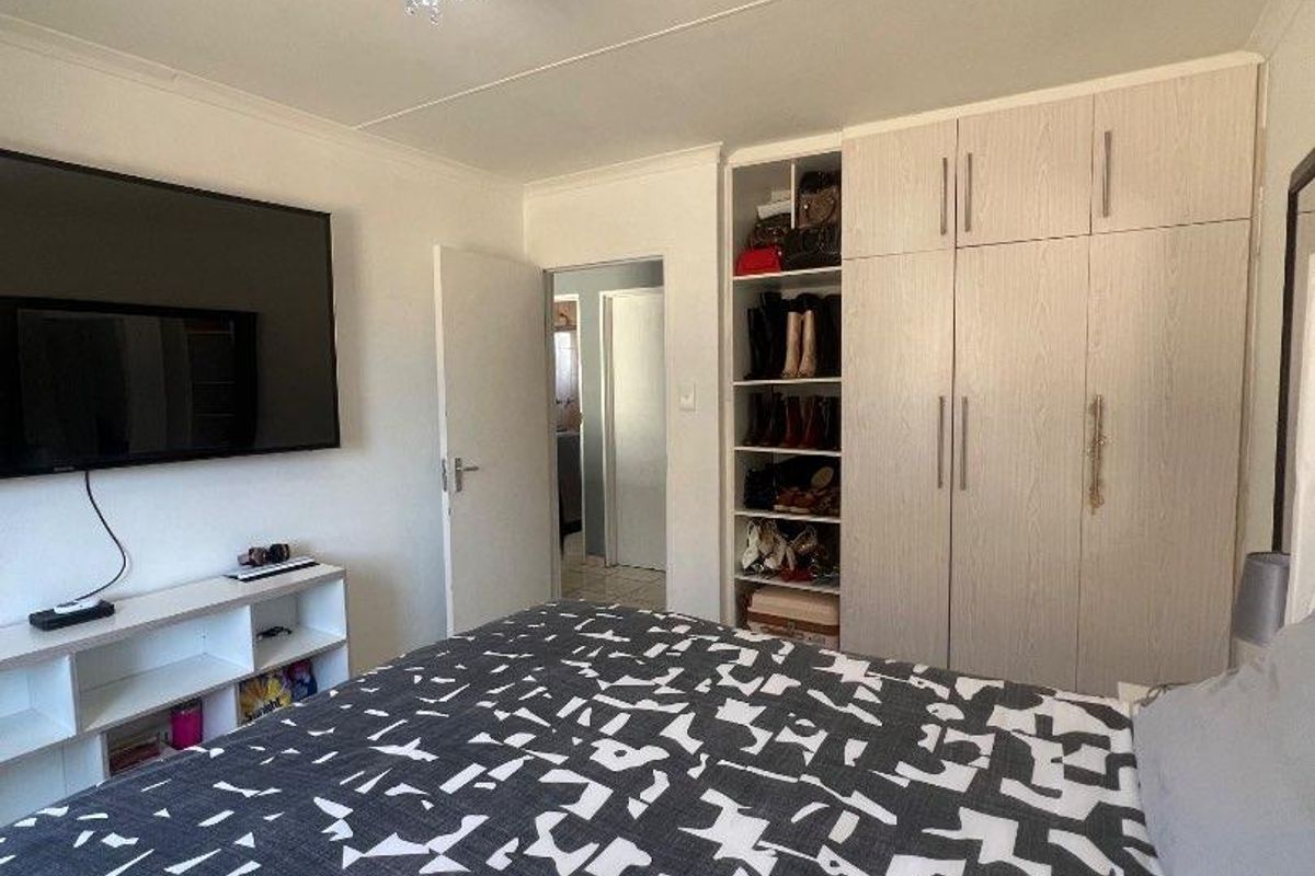 A well-maintained bedroom featuring built-in cupboards with integrated shelving and a modern ceiling light fixture.