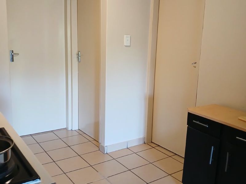 A functional kitchen area featuring tiled flooring, built-in cabinetry, and a hob, providing access to multiple internal rooms.