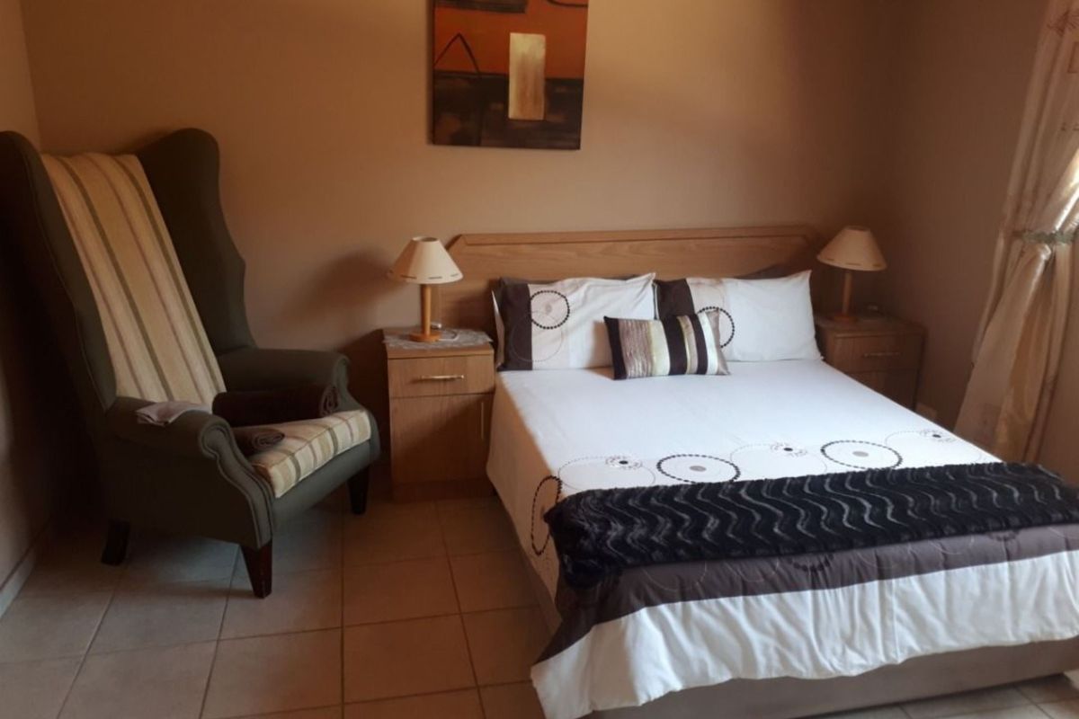 A bedroom featuring tiled flooring and a built-in wooden headboard with matching bedside tables.
