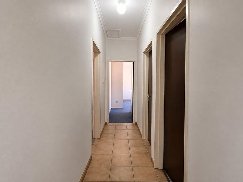 A clean and functional hallway featuring tiled flooring and multiple internal doors providing access to adjacent rooms.