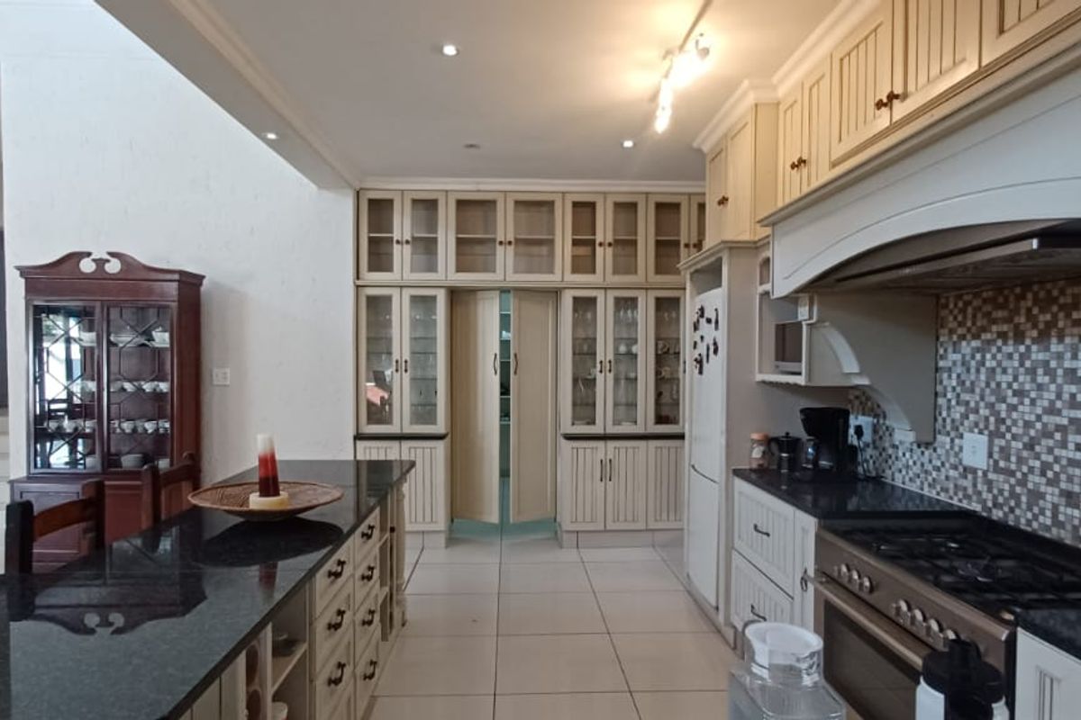 Spacious kitchen featuring granite countertops, extensive built-in cabinetry, a central island, and a gas stove with a decorative extractor hood.