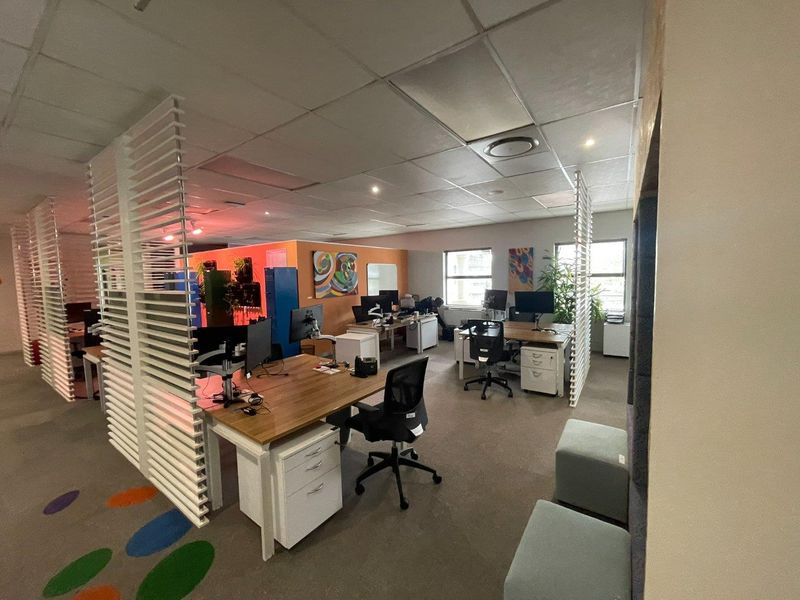 Open-plan office space featuring suspended ceilings, recessed lighting, and decorative slatted room dividers, providing a functional workspace environment.