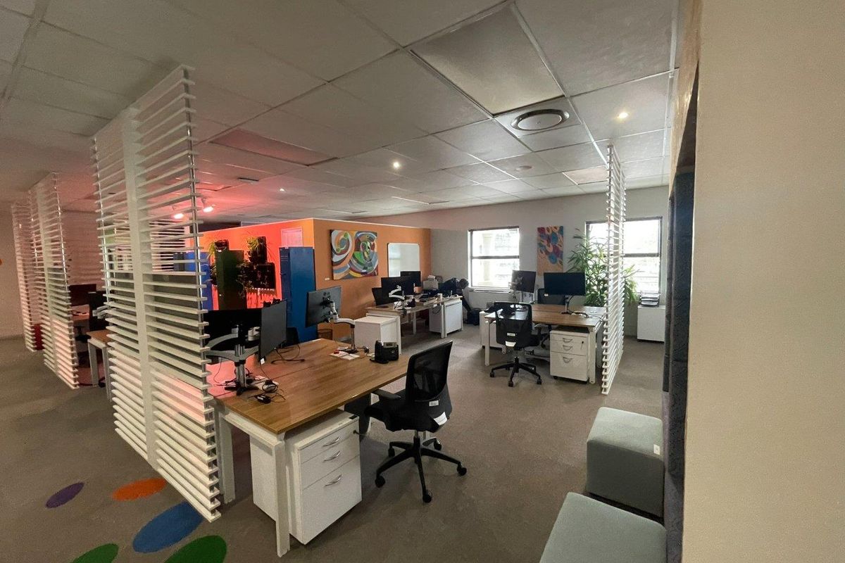 Open-plan office space featuring suspended ceilings, recessed lighting, and decorative slatted room dividers, providing a functional workspace environment.