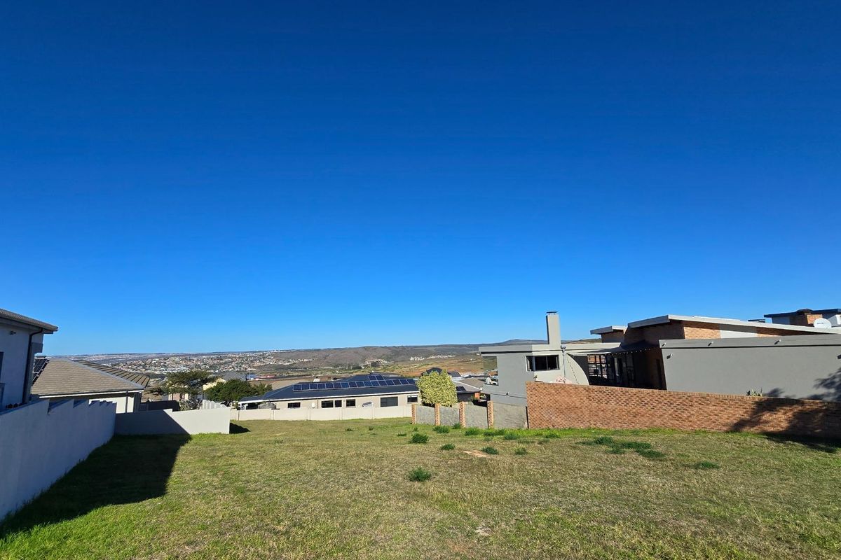 A vacant residential plot featuring a gentle slope, clear boundaries, and expansive views of the surrounding landscape and neighboring properties.