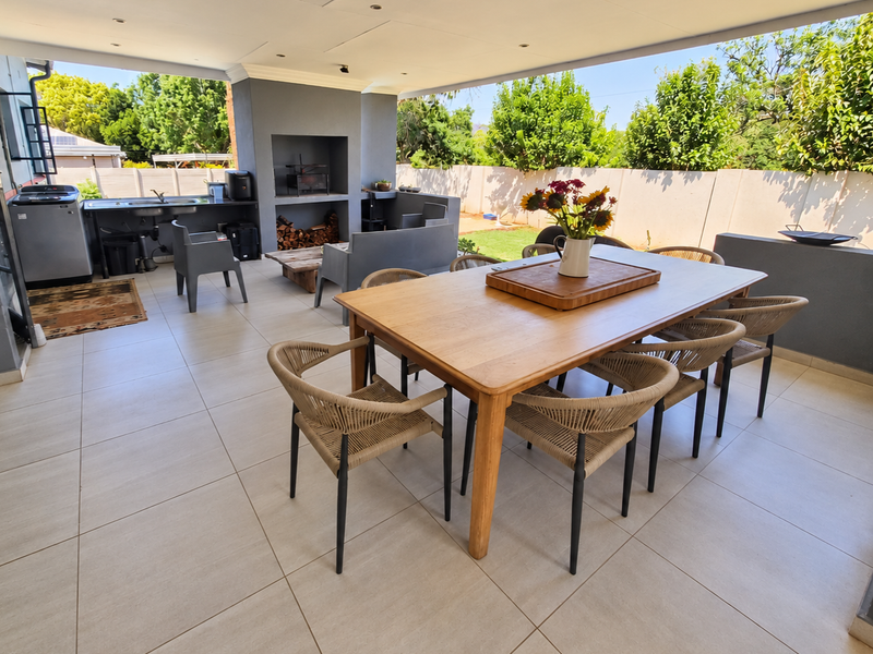 Spacious covered patio featuring a built-in braai, outdoor sink, and large format floor tiles, perfect for outdoor dining and entertaining.