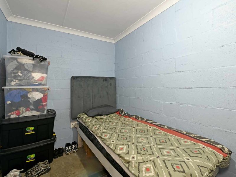 A compact bedroom featuring exposed blockwork walls and a simple finish, offering a functional space that could be enhanced with modern interior updates.