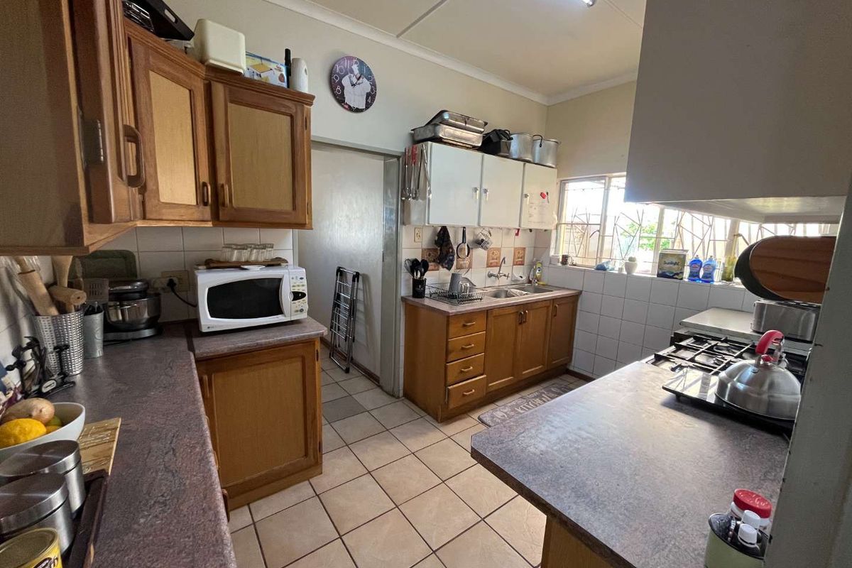 A functional kitchen featuring wooden cabinetry, laminate countertops, a double bowl sink, and a gas hob, offering potential for modernization.