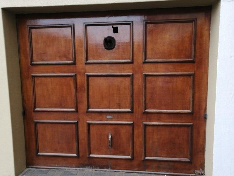 A wooden garage door featuring a panel with visible damage and a missing section, requiring repair or replacement.