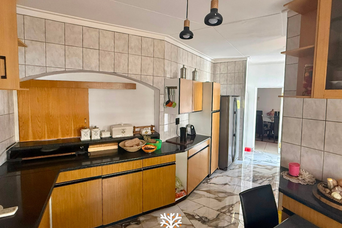 A functional kitchen featuring laminate cabinetry, granite countertops, tiled backsplash, and marble-look floor tiles, illuminated by modern pendant lighting.