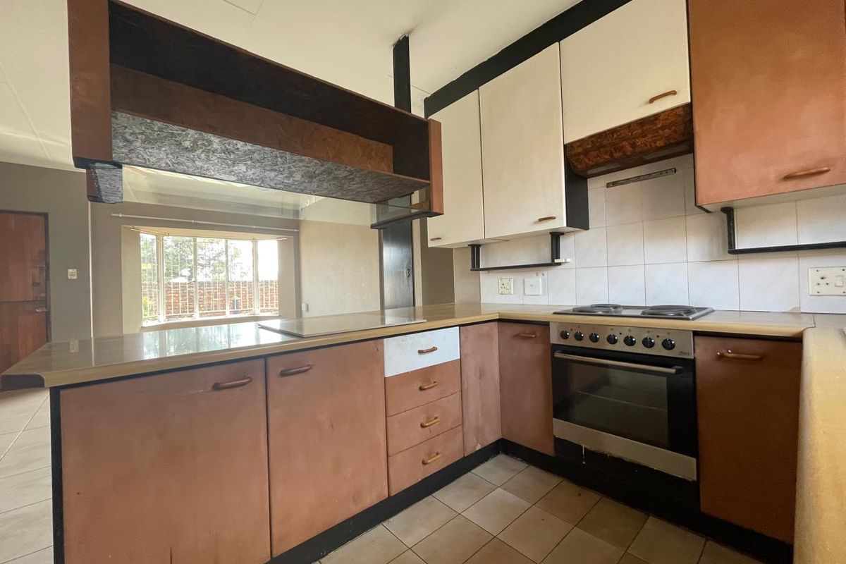 A dated kitchen featuring built-in cabinetry, an electric oven and hob, tiled backsplash, and tiled flooring, offering potential for a modern renovation.
