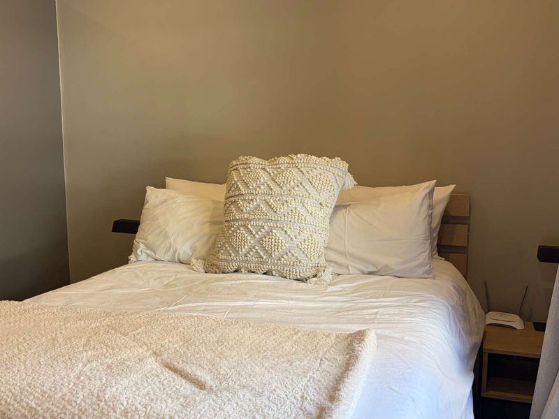 A cozy bedroom featuring neutral wall tones and a built-in cupboard, providing a comfortable and functional sleeping space.