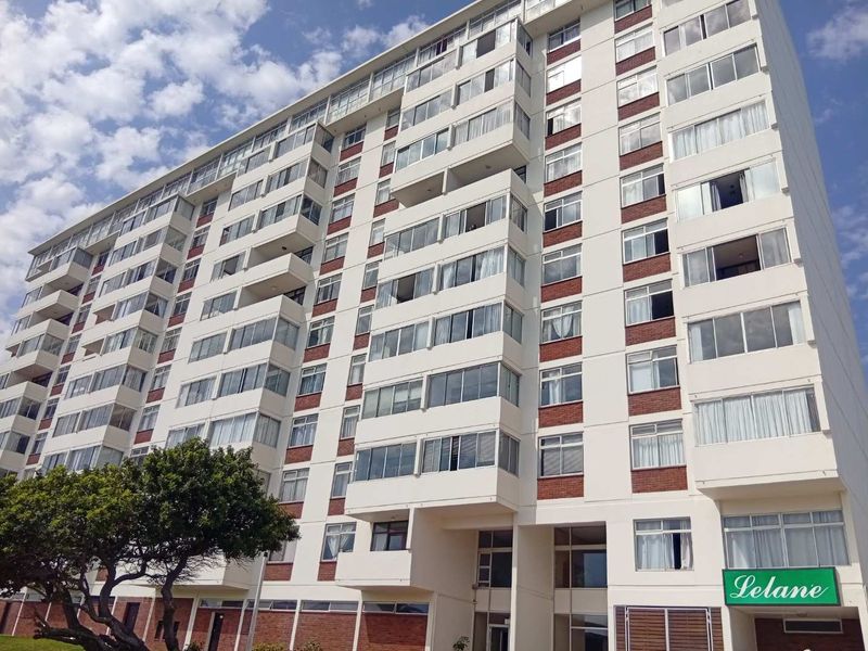 A low-angle exterior view of the Lelane apartment building, showcasing its multi-story facade with enclosed balconies and brick detailing.