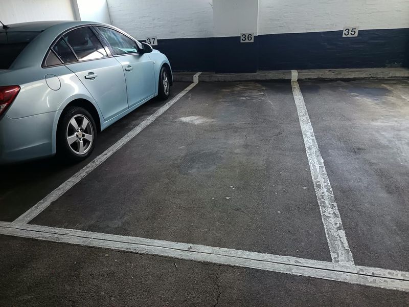 Covered parking area featuring marked bays and painted brick walls within an apartment complex garage.