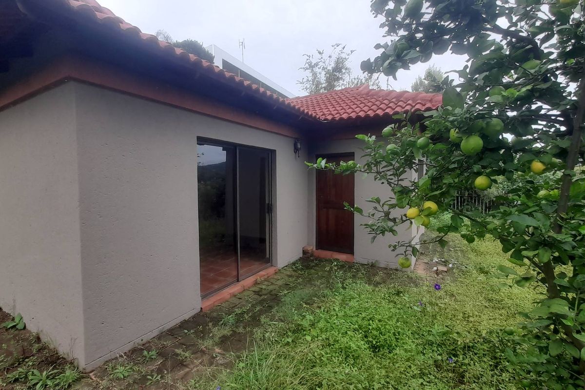Exterior view of the property featuring a tiled roof, sliding glass doors, and a wooden entrance door, set within a garden area.