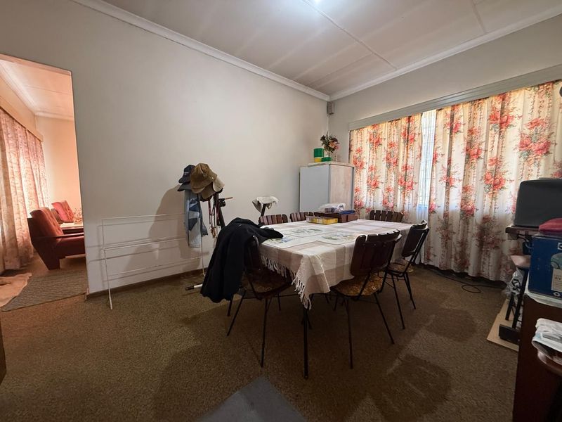 A dining room featuring carpeted flooring and coved ceilings, with a view into an adjacent living area.
