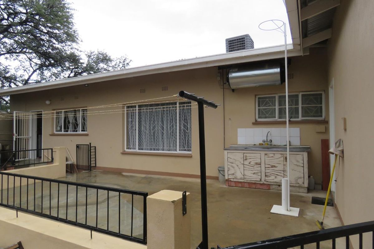 Rear exterior view featuring a concrete patio, outdoor sink area with cabinetry, and a wall-mounted geyser unit.