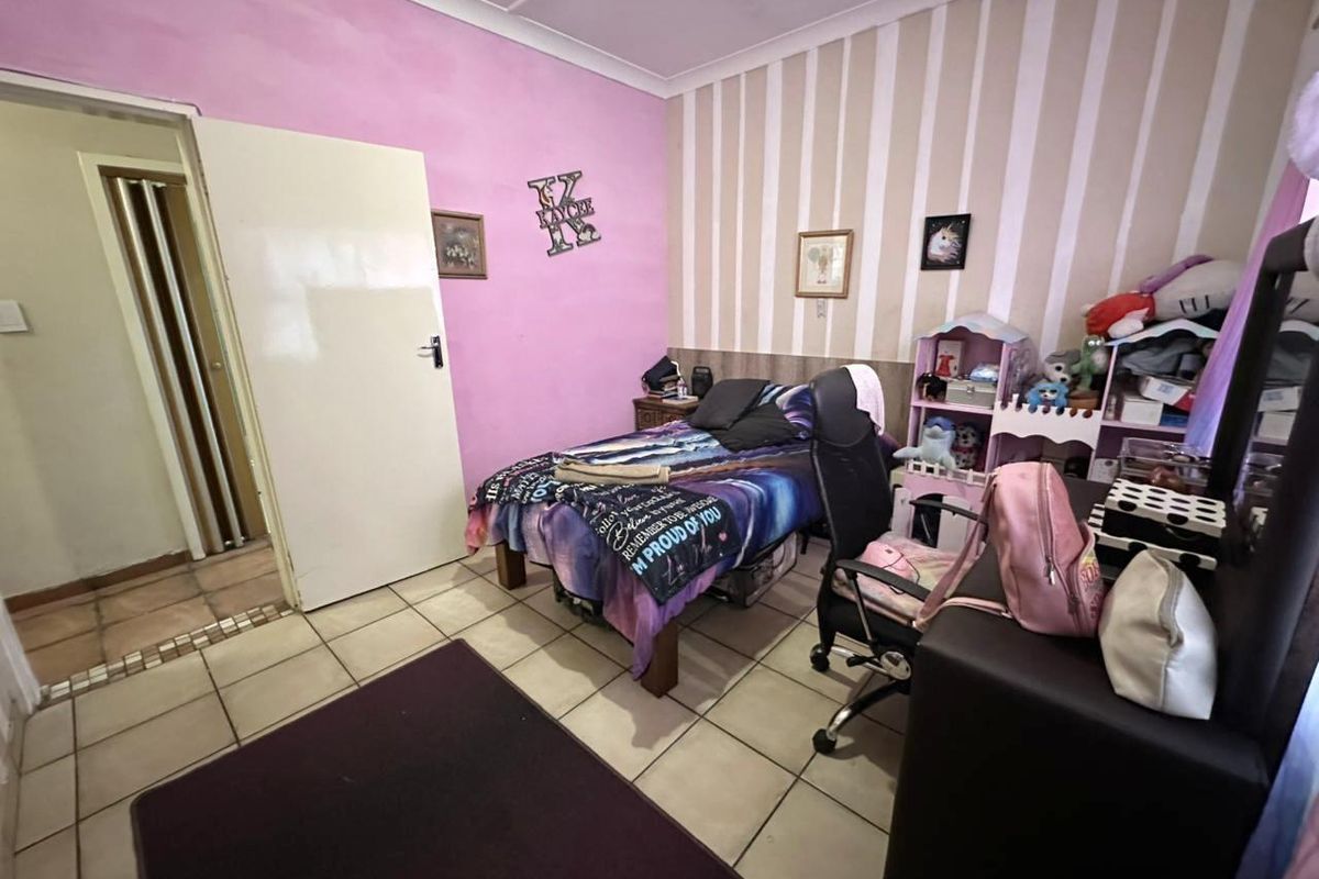 A bedroom featuring tiled flooring, a combination of painted and wallpapered walls, and a standard interior door leading to an adjacent space.
