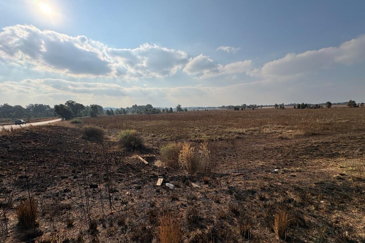 A wide-angle view of an expansive agricultural land parcel featuring dry, scorched vegetation and open terrain under a bright sky.