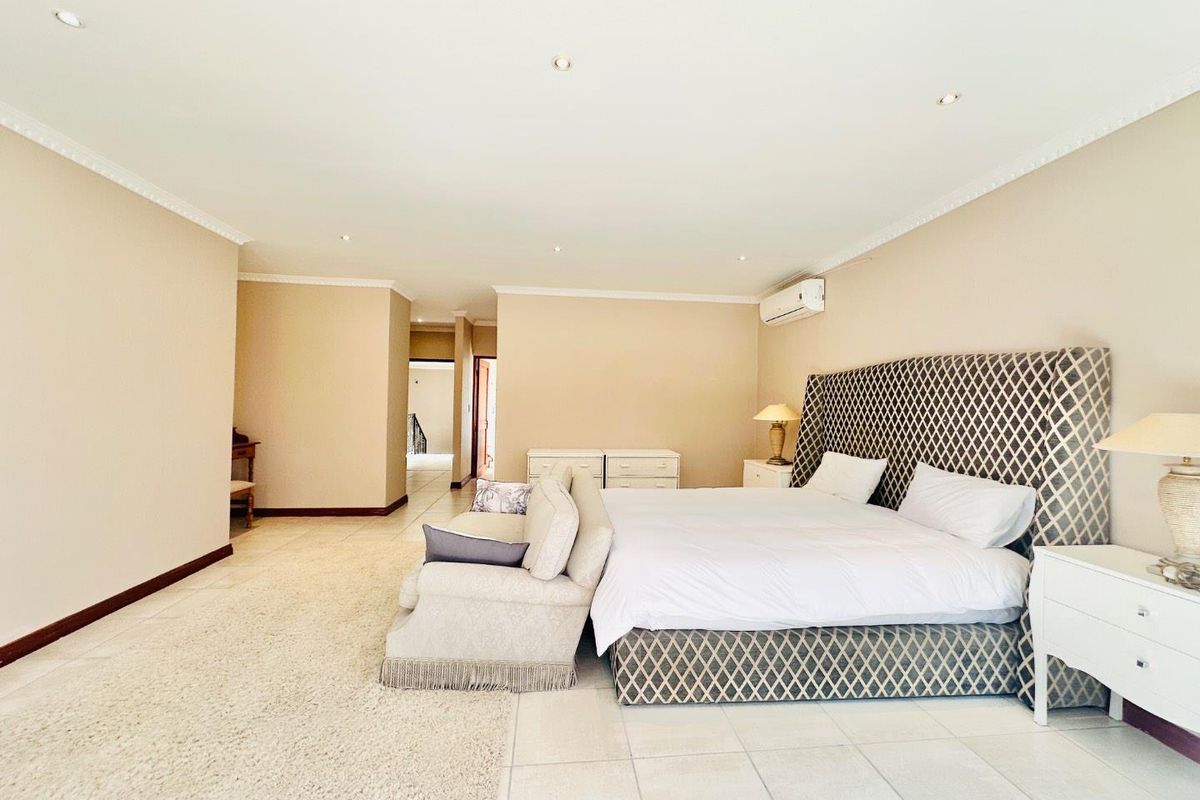 Spacious bedroom featuring tiled flooring, recessed ceiling lighting, and a wall-mounted air conditioning unit.