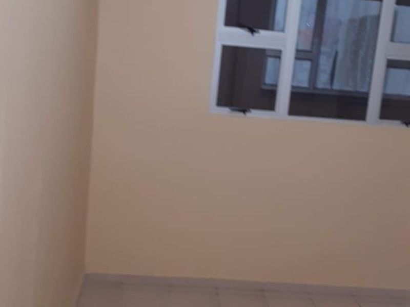 An empty bedroom featuring neutral wall paint, tiled flooring, and an aluminium-framed window.