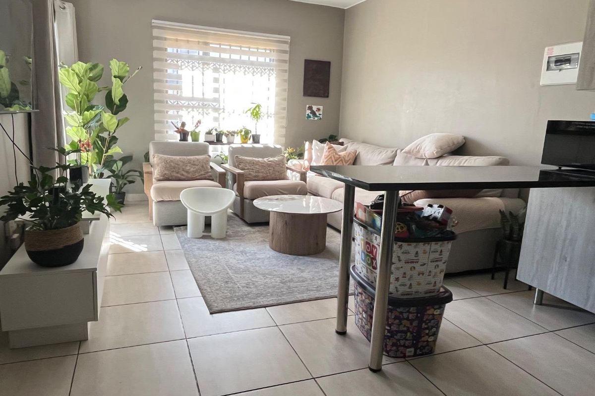A well-lit living room featuring neutral tiled flooring and modern roller blinds, providing a comfortable and functional open-plan living space.