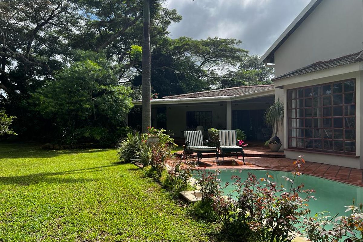 A private rear garden featuring a swimming pool, terracotta tiled patio, and mature landscaping, providing a tranquil outdoor living space.