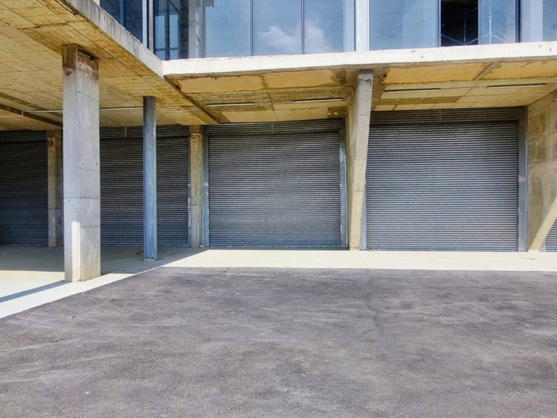 Industrial property featuring multiple secure roller shutter garage doors and a covered concrete parking area.