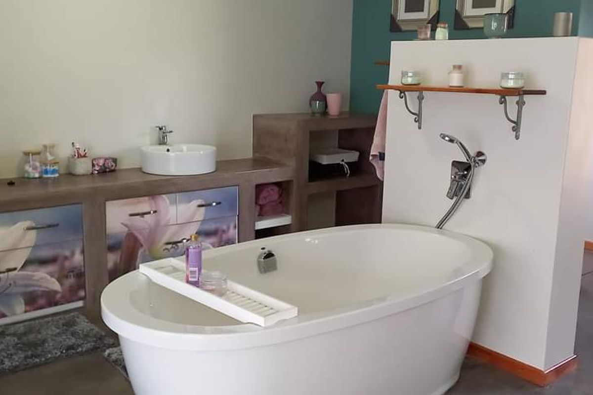 A modern bathroom featuring a freestanding bathtub, dual vessel sinks on a custom vanity, and polished concrete flooring.