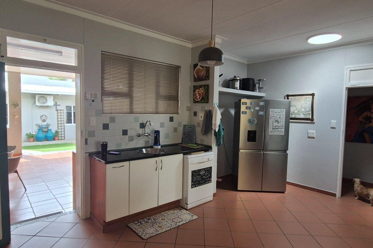 A functional kitchen area featuring a single sink, built-in cabinetry, and tiled flooring, with direct access to an outdoor patio space.