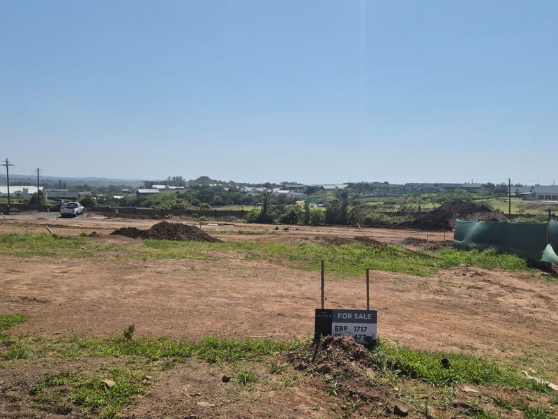 A vacant residential plot of land featuring open space and boundary fencing, situated in a developed estate with surrounding neighborhood views.