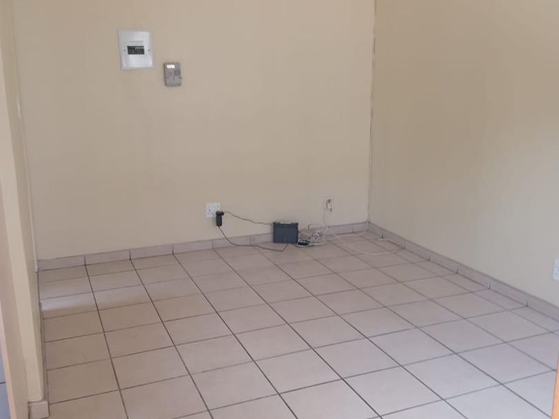 An empty living room featuring neutral tiled flooring and cove cornicing, providing a clean and versatile space ready for personalization.