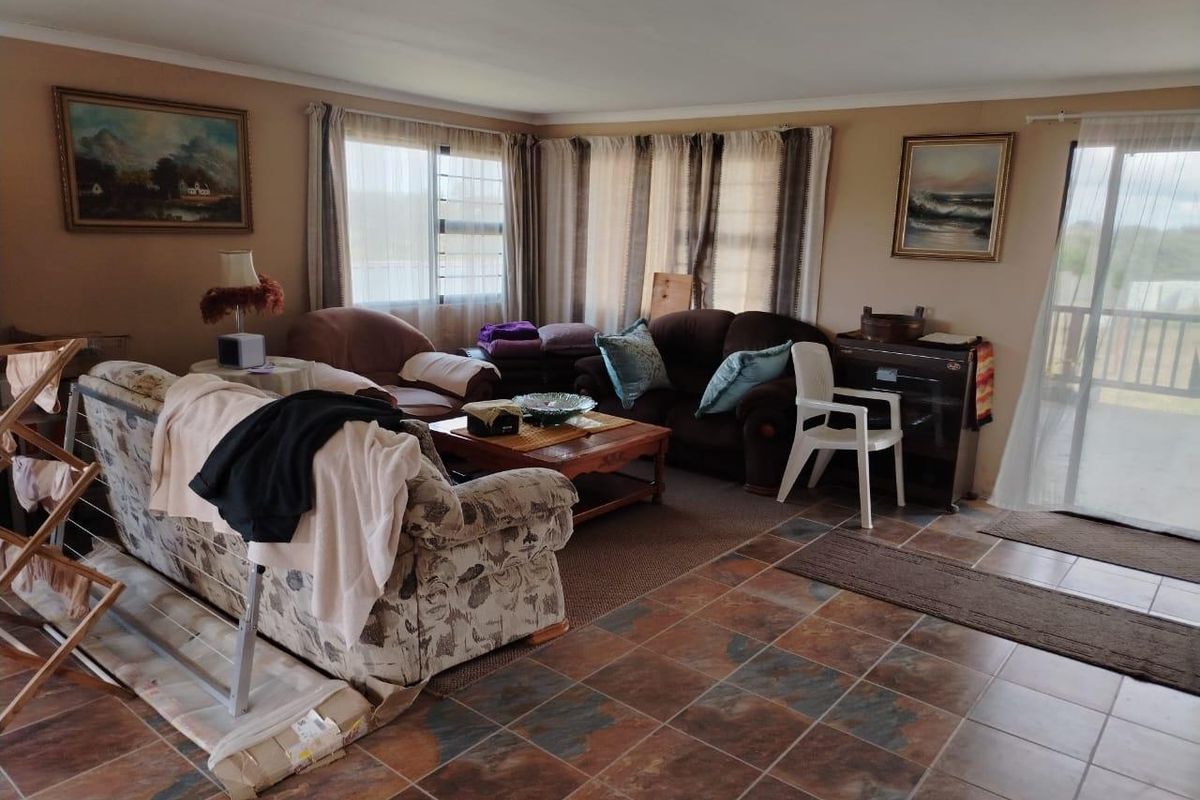 A spacious living room featuring tiled flooring, large windows for natural light, and a sliding glass door providing access to the outdoor area.