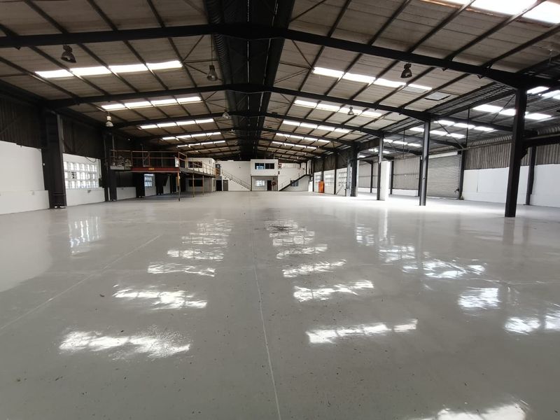Spacious industrial warehouse featuring a polished epoxy floor, high-clearance steel portal frame, mezzanine level, and ample natural light through integrated skylights.