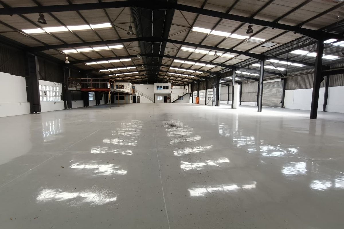 Spacious industrial warehouse featuring a polished epoxy floor, high-clearance steel portal frame, mezzanine level, and ample natural light through integrated skylights.