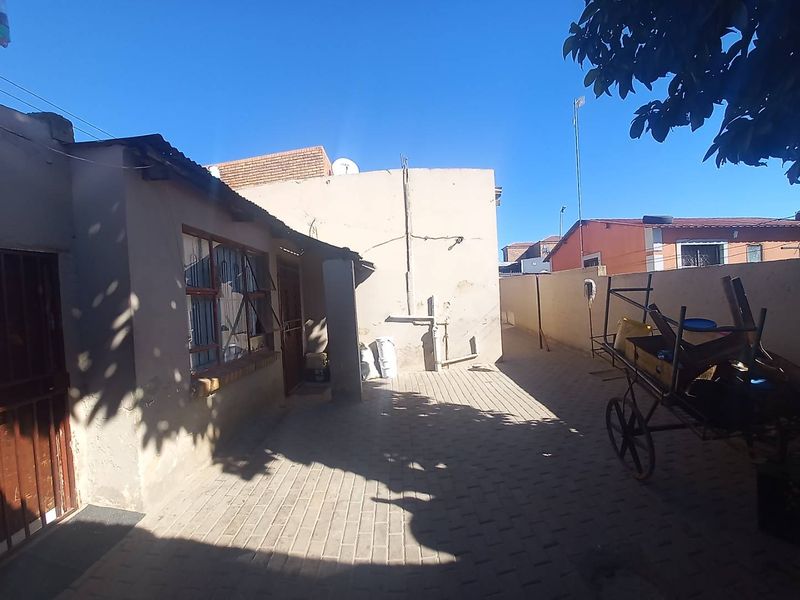 A paved rear courtyard area featuring boundary walls and security features, offering a functional outdoor space with potential for landscaping improvements.