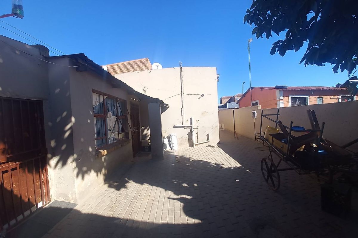 A paved rear courtyard area featuring boundary walls and security features, offering a functional outdoor space with potential for landscaping improvements.