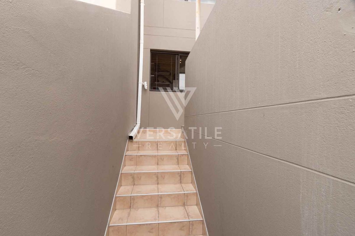 An exterior staircase with tiled steps leading to an upper level, flanked by solid rendered walls and a vertical drainage pipe.