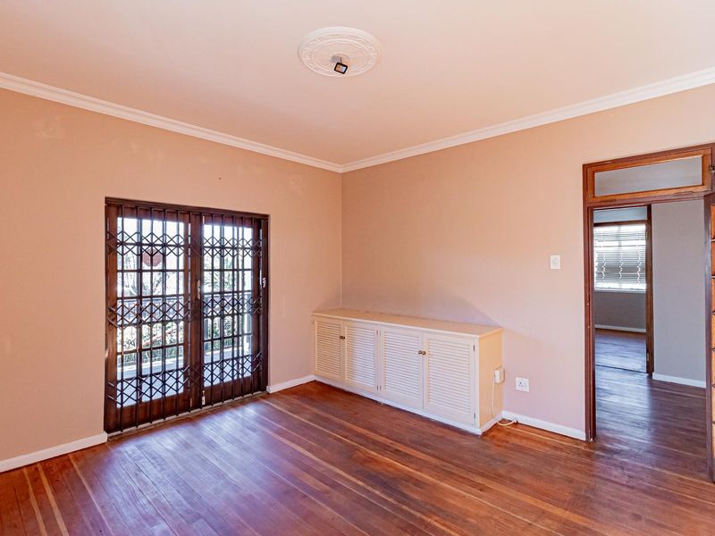 An empty living room featuring hardwood flooring, built-in cabinetry, and a security gate leading to an outdoor area.