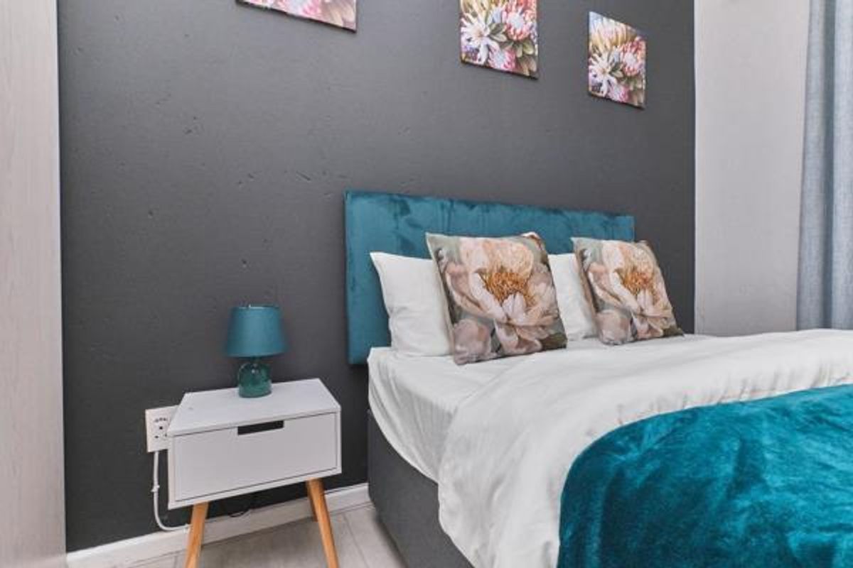 A well-maintained bedroom featuring a dark accent wall and neutral flooring, providing a comfortable and modern sleeping space.