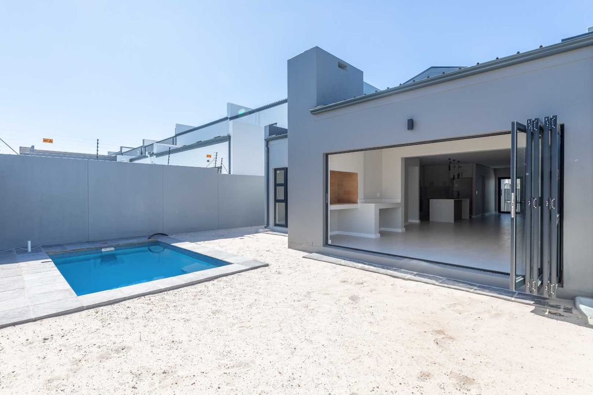Rear exterior view featuring a swimming pool, built-in braai area, and large bi-fold doors opening into the main living space.