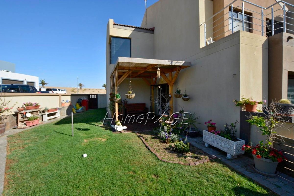 Rear view of the townhouse featuring a private garden area and a timber-framed covered patio.