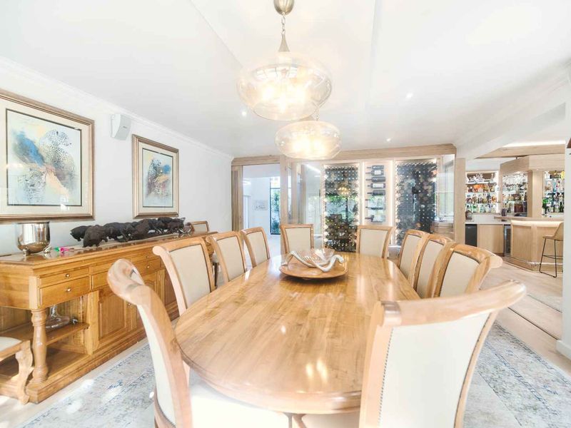 Elegant dining room featuring a built-in wine cellar and an adjacent bar area, finished with sophisticated lighting and classic architectural details.