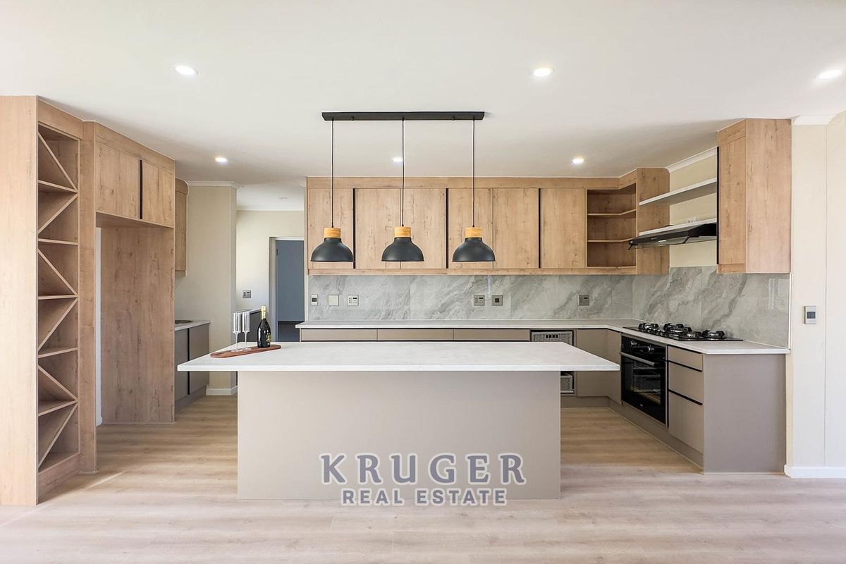 Modern kitchen featuring a central island, stone countertops, built-in oven, gas hob, and contemporary light wood cabinetry with a stone splashback.